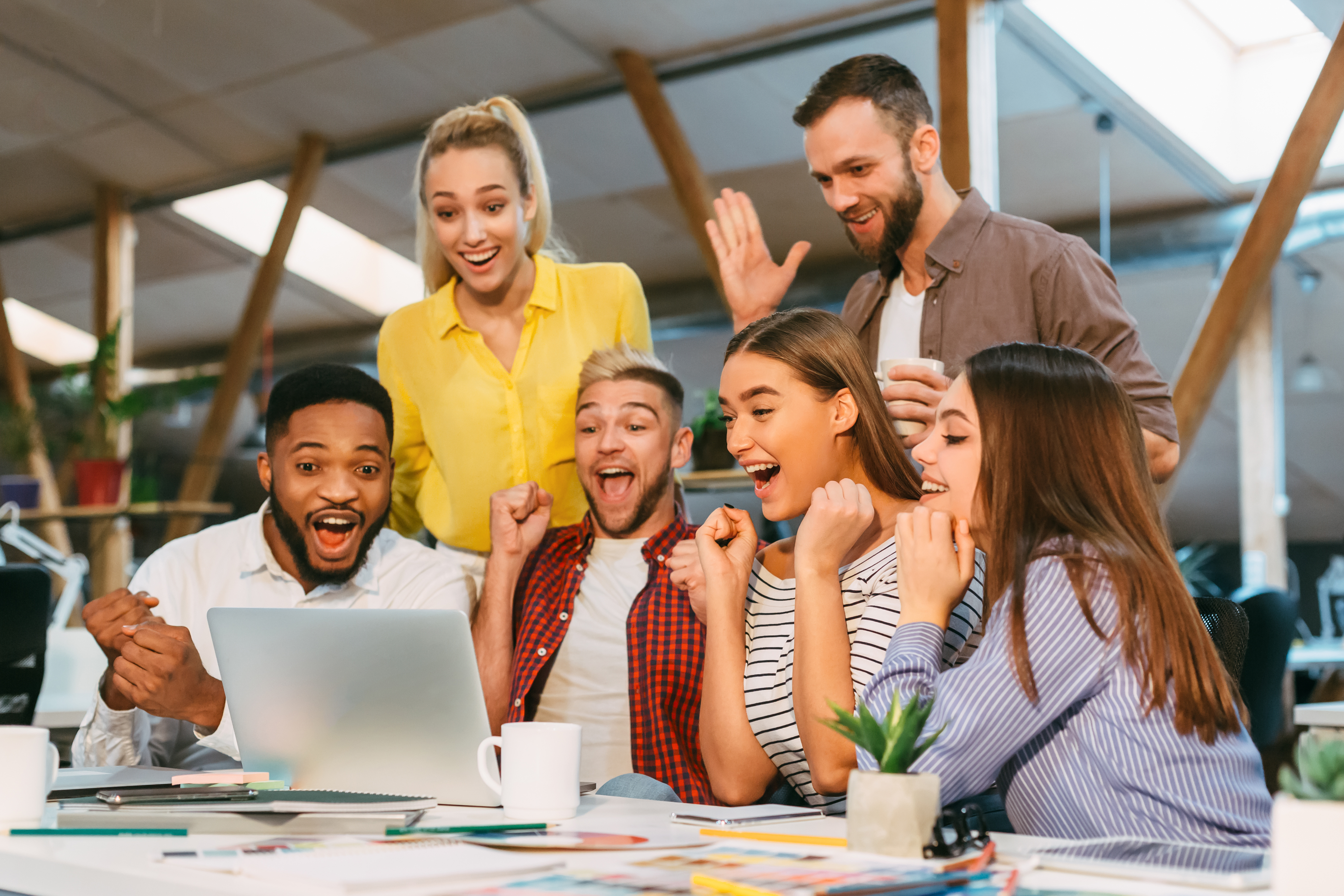 Successful team. Designers enjoying success, looking at laptop screen, winning tender